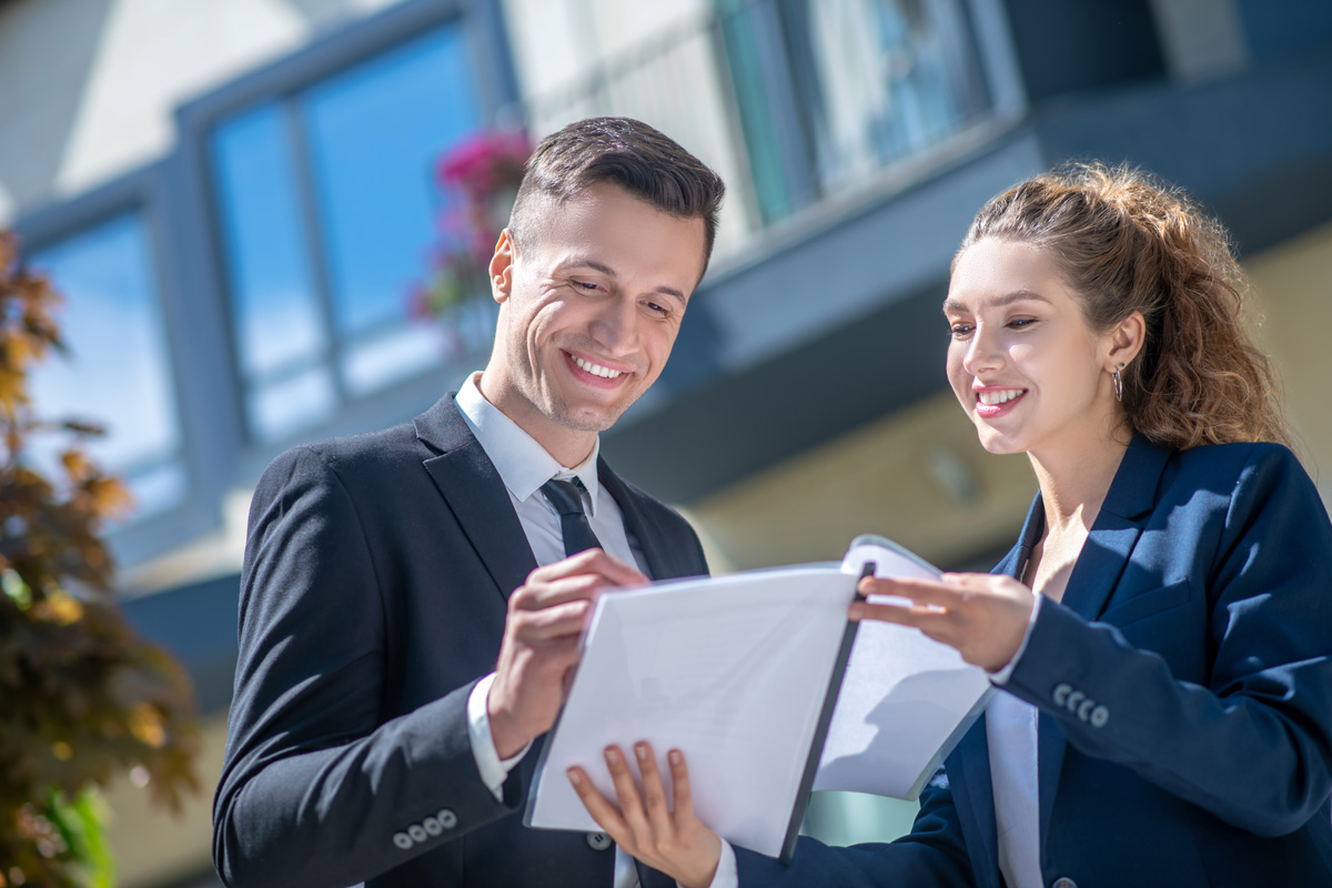 Two smiling real estate brokers reviewing paperwork.